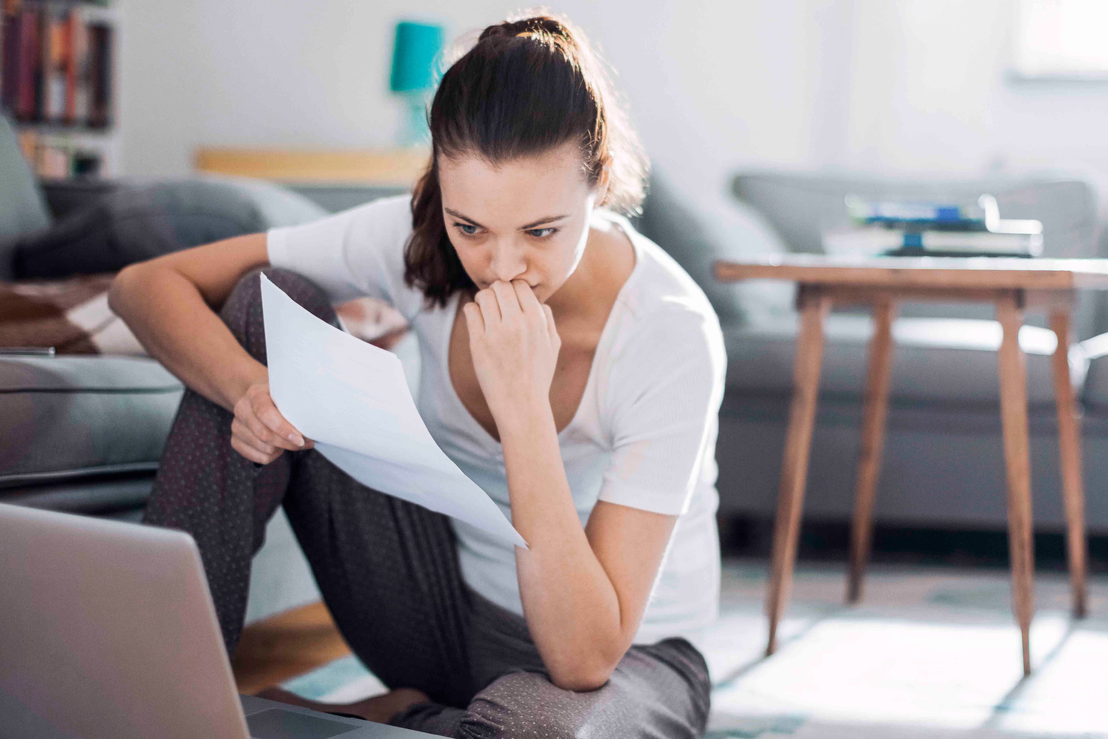 Kvinne som sitter på gulvet med laptop